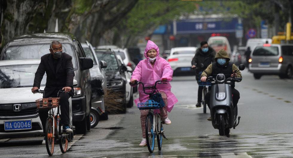 Las personas que usan máscaras viajan a lo largo de una calle en Wuhan, en la provincia central de Hubei de China. (AFP/Noel Celis).