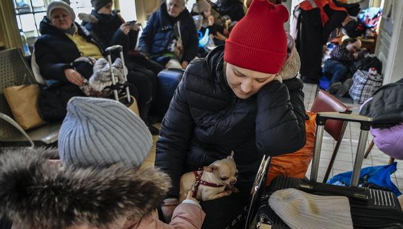 Una mujer con un perro pequeño y un niño esperan junto con otros refugiados en la estación de tren de Przemysl, cerca de la frontera entre Polonia y Ucrania, que se convirtió en uno de los principales centros de reubicación, el 11 de marzo de 2022. (Foto: Louisa GOULIAMAKI / AFP)