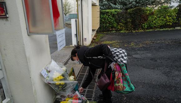 Una mujer deposita flores en la entrada de la Gendarmería en Ambert, en el centro de Francia, el 23 de diciembre de 2020, después de que tres gendarmes fueron asesinados. (Foto: Olivier CHASSIGNOLE / AFP)