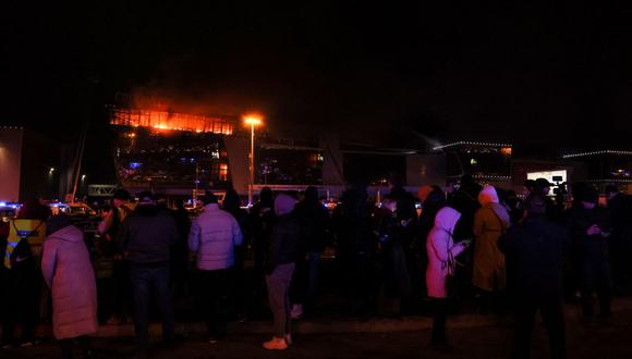 La gente se agolpa frente a la sala de conciertos Crocus City Hall en llamas tras el tiroteo en Krasnogorsk, en las afueras de Moscú, el 22 de marzo de 2024 | Foto: STRINGER / AFP
