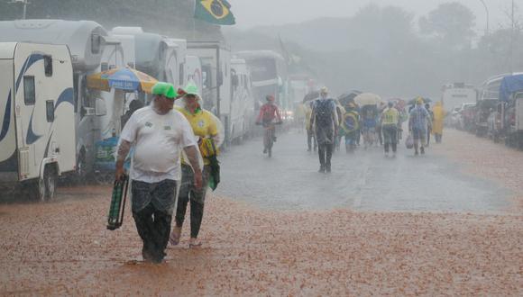 Partidarios del presidente brasileño Jair Bolsonaro caminan por un campamento inundado por fuertes lluvias durante una manifestación para pedir la intervención federal frente a la sede del Ejército en Brasilia el 15 de noviembre de 2022. (Foto de Sergio Lima / AFP)