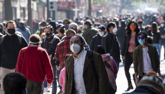 Las personas usan máscaras faciales mientras caminan por un paseo peatonal en el centro de Santiago, luego de la flexibilización de las restricciones de bloqueo en medio de la pandemia COVID-19. (Martin BERNETTI/AFP).