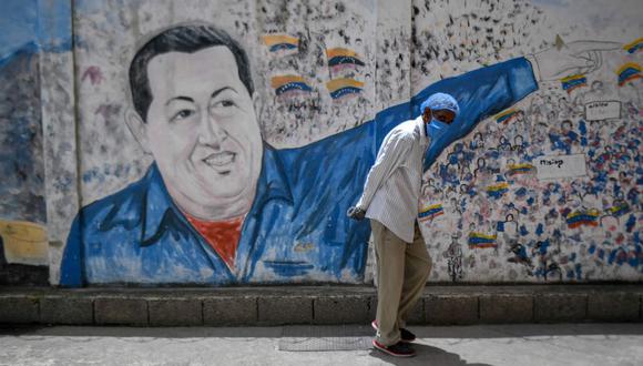 Un hombre con una máscara protectora pasa junto a un mural que representa al fallecido presidente de Venezuela, Hugo Chávez, en el Hospital Pérez de León del barrio de Petare.  (AFP/Federico PARRA).