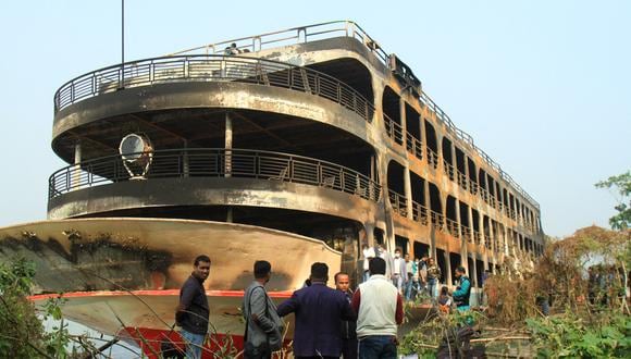 La gente observa el ferri quemado mientras está anclado a lo largo de la costa, un día después de que se incendió y mató al menos a 37 personas en Jhalkathi, Bangladés. (Foto: Arifur Rahman / AFP)
