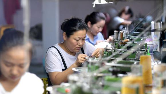 Empleados en una fábrica en el condado de Xiayi, en la provincia central de Henan, China. Inversiones en la industria china cayeron a un mínimo histórico en los primeros 7 meses del año por la desaceleración de las ventas minoristas. (Foto: AFP)
