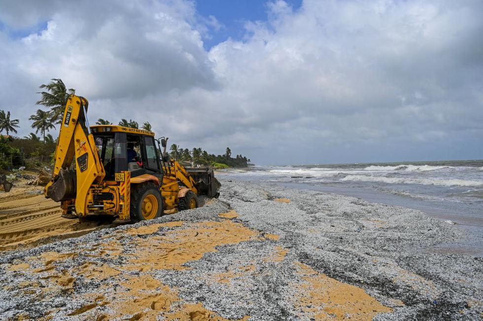 Una excavadora retira los escombros arrastrados a tierra del buque portacontenedores "MV X-Press Pearl", registrado en Singapur, que ha estado ardiendo por varios días en el mar frente al puerto de Colombo en Sri Lanka, el 29 de mayo de 2021. (ISHARA S. KODIKARA / AFP).