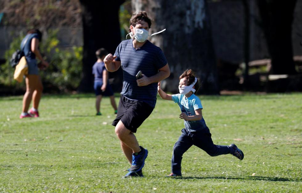 Un padre y su hijo con máscaras faciales juegan en un parque después de que se levantaron parcialmente las restricciones para los niños en la ciudad de Buenos Aires durante el brote de la enfermedad por coronavirus. (REUTERS/Agustin Marcarian).