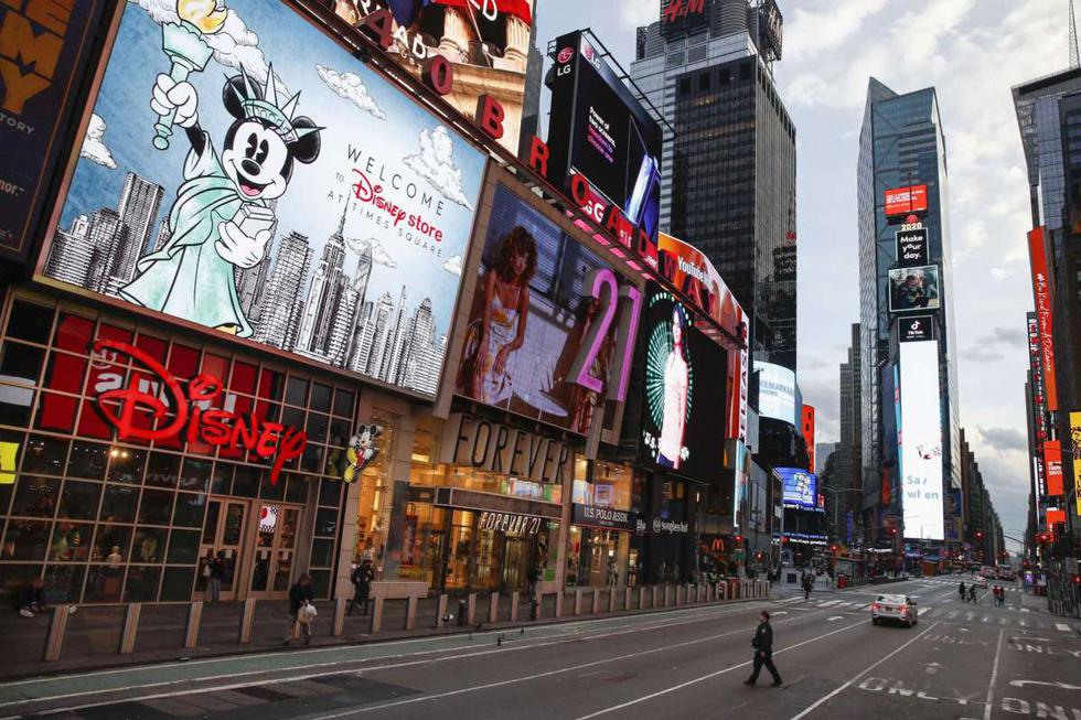 Un policía cruza una 7ma Avenida desierta en Times Square el 20 de marzo del 2020. Casi no se ve gente en las calles de Nueva York por el coronavirus. Teatros y negocios, no obstante, siguen iluminados como si nada estuviese sucediendo. (Foto: AP)