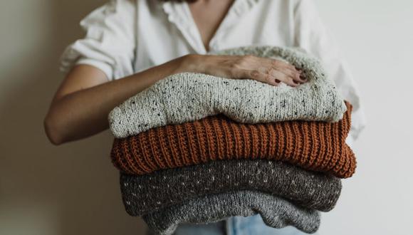 Una mujer sosteniendo cuatro chompas de lana tras lavarlas. | Imagen referencial: Pexels