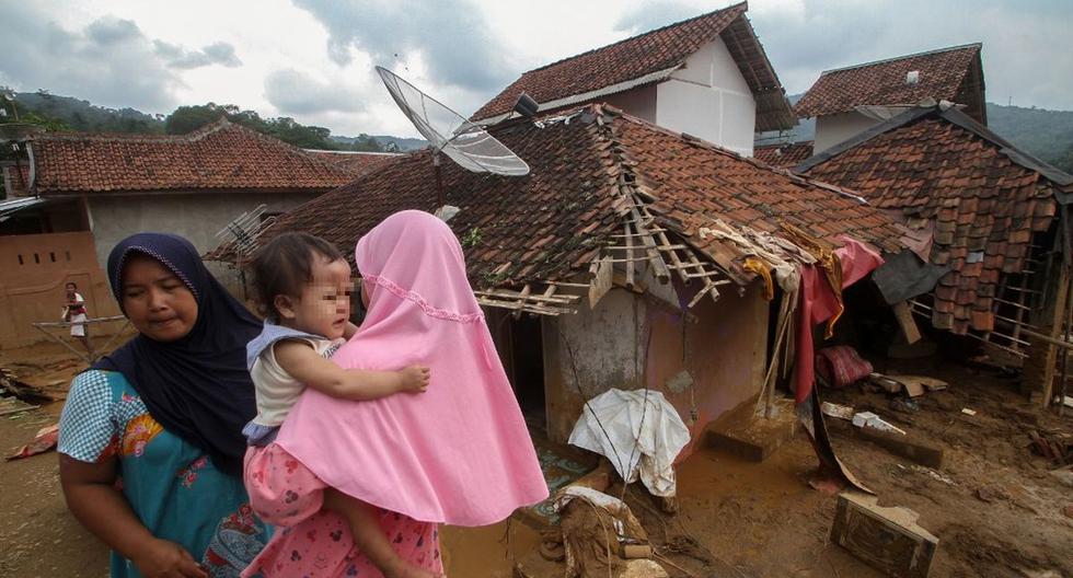 Los aldeanos caminan frente a su casa dañada por una inundación en el pueblo de Banjar Irigasi en Lebak. (AFP)