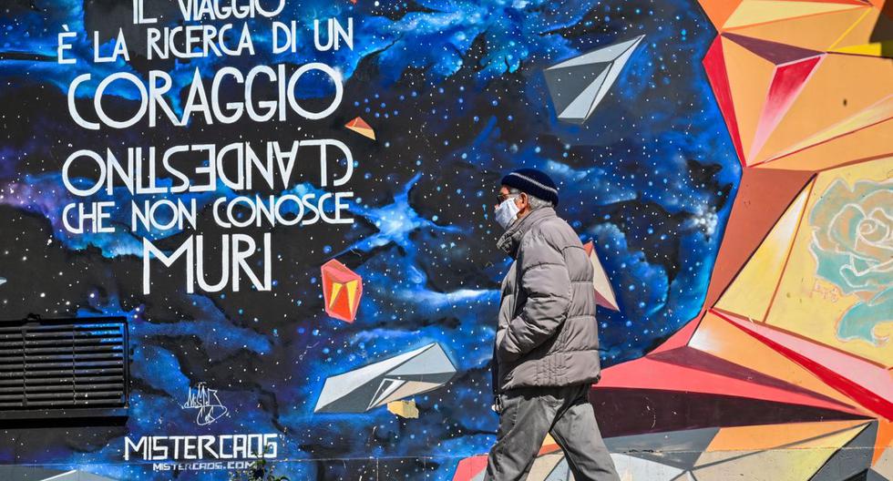 Un hombre con una máscara facial pasa junto a un mural en el distrito de Trullo de Roma el 18 de marzo de 2020. (ANDREAS SOLARO/AFP/Referencial).
