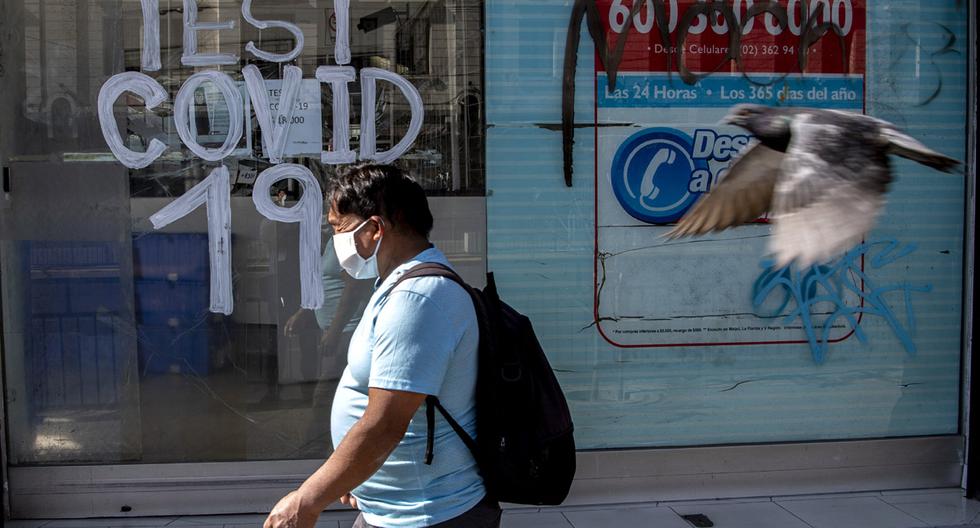 Imagen referencial. Una persona pasa junto a una farmacia donde se realizan pruebas de COVID-19 en la comuna de Recoleta, que fue puesta en cuarentena para frenar la propagación del nuevo coronavirus, en Santiago. (AFP/MARTIN BERNETTI)