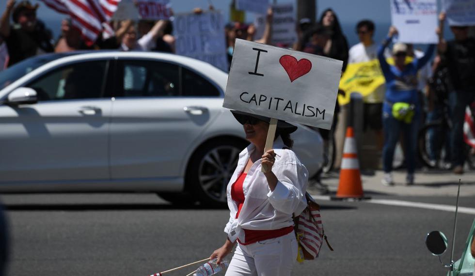 Un manifestante sostiene un cartel que dice "Amo el capitalismo" mientras protestaba contra la orden del estado de quedarse en casa en medio de la pandemia de coronavirus, en California. (Foto: AFP/Robyn Beck)