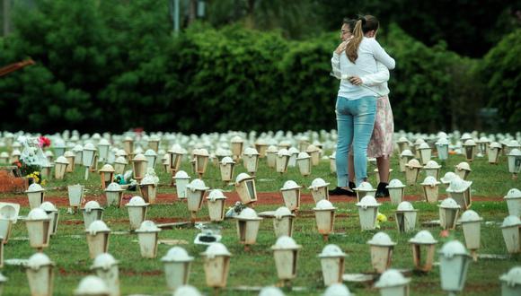 Dos mujeres lloran durante el entierro de una víctima de COVID-19, en el cementerio de Campo da Esperança en la ciudad de Brasilia (Brasil). (Foto: EFE/Joédson Alves)