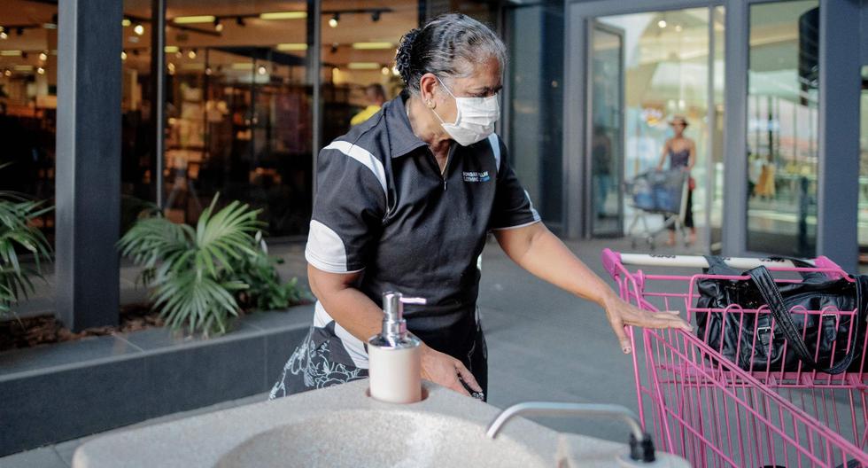 Una mujer busca un carrito de compras después de lavarse las manos en Africa Mall en Johannesburgo. Imagen del 20 de marzo de 2020. (AFP).