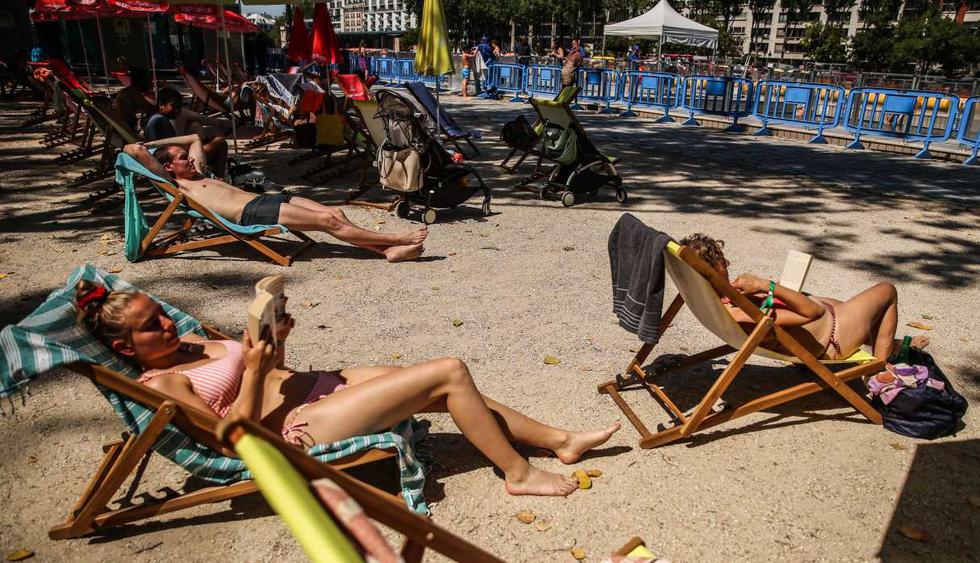 Las personas se sientan en sillas de playa al sol junto a una piscina temporal habilitada en el canal de Bassin de la Villette en París, Francia. (EFE/EPA/MOHAMMED BADRA).