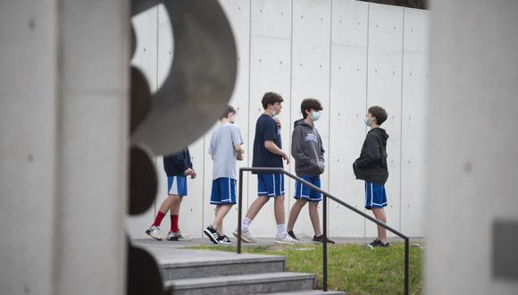 Un grupo de niños en edad escolar usa mascarillas mientras habla en un jardín de esculturas en el Distrito de los Museos en Houston, Texas (Estados Unidos), el 10 de marzo de 2021. (Mark Felix / AFP).