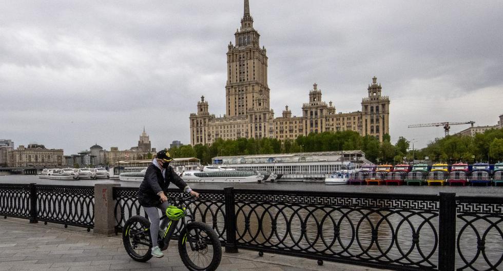 Imagen referencial. Una mujer usa una máscara protectora mientras monta una bicicleta a lo largo del terraplén del río Moskva en el centro de Moscú. (Yuri KADOBNOV / AFP).