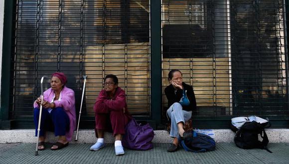 Los pacientes en tratamiento de diálisis esperan fuera de una clínica cerrada durante un apagón en Caracas el 26 de marzo de 2019. (Foto: AFP)