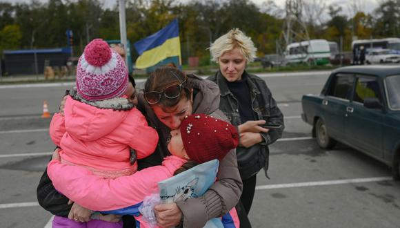 Una mujer ucraniana y sus hijos son recibidos por un pariente después de que pudieron salir del territorio ocupado por Rusia de Kherson, en Zaporizhzhia, el 21 de octubre de 2022, en medio de la invasión de Rusia a Ucrania. (Foto de BULENT KILIC / AFP)