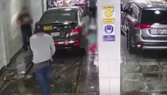 Momento en que uno de los delincuentes ingresa al local de lavado de autos y amenaza con un arma al taxista. (Captura: América Noticias)