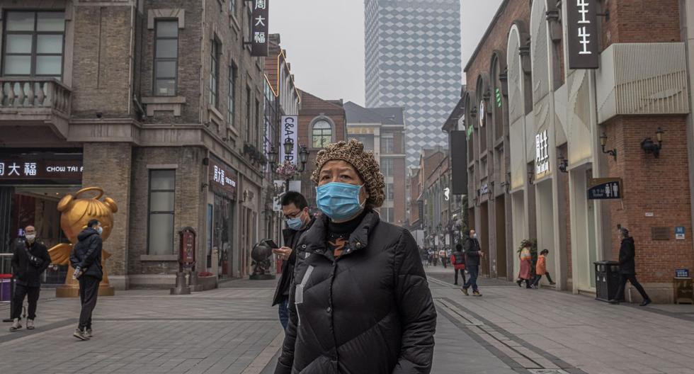 Una mujer con una máscara protectora visita un centro comercial el día del primer aniversario del encierro de Wuhan, en Wuhan, China, el 23 de enero de 2021. (EFE/EPA/ROMAN PILIPEY).