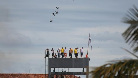 Presos son vistos en lo alto de una torre de la prisión de Puraquequara en Manaus, estado de Amazona, Brasil, durante una rebelión para exigir mejores condiciones dentro de la cárcel. Siete guardias fueron tomados como rehenes, el 2 de mayo de 2020. (Foto: MICHAEL DANTAS / AFP)