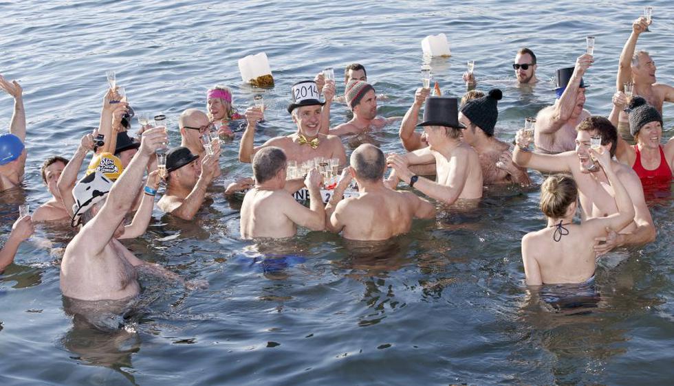 Las personas brindaron con champaña mientras nadaron en las frías aguas del Lago de Ginebra para celebrar el Año Nuevo en Suiza. (AP)