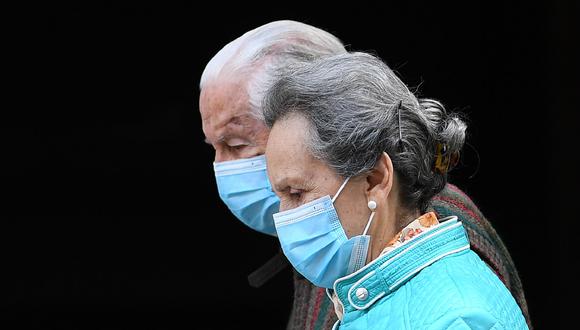 Una pareja de ancianos camina en Madrid (España) con mascarillas para evitar el contagio de la enfermedad COVID-19. (Foto: AFP/Gabriel BOUYS)