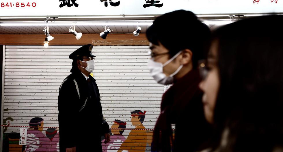 Imagen referencial. Un oficial de policía (izquierda) con una máscara facial para ayudar a prevenir la propagación del coronavirus Covid-19 camina por una calle de Tokio. (Behrouz MEHRI / AFP).