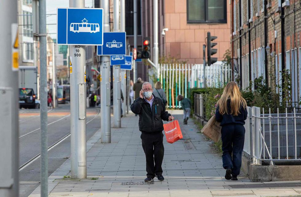 Un hombre que usa una mascarilla como precaución contra la transmisión del nuevo coronavirus camina por una calle en Dublín (Irlanda). (AFP / Paul Faith).