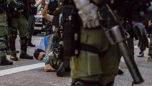 La policía detiene a un hombre mientras patrulla las calles de Hong Kong, después de que los manifestantes convocaron una manifestación para protestar contra la decisión del gobierno de posponer las elecciones del consejo legislativo debido alCOVID-19 y la ley de seguridad nacional.(DALE DE LA REY / AFP)