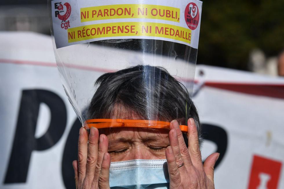 Un miembro de la profesión de enfermería usa una mascarilla protectora y una visera que dice, 'sin perdón, sin olvido, sin recompensa, sin medalla' durante una manifestación en París. (AFP / Alain JOCARD).
