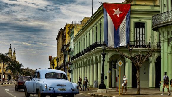Un viejo automóvil estadounidense pasa cerca de una bandera cubana que cuelga de un edificio en La Habana, el 17 de noviembre de 2021. (Foto: YAMIL LAGE / AFP)