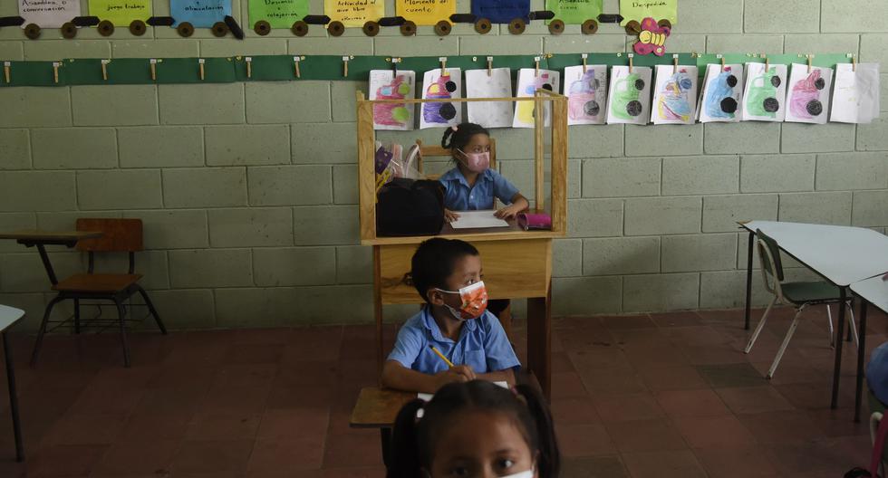Allison López utiliza un pupitre diseñado por su padre y que le permite protección y mantener distancia para prevenir la Covid-19, en la escuela de Ciudad Delgado (El Salvador). (EFE/ Vladimir Chicas).