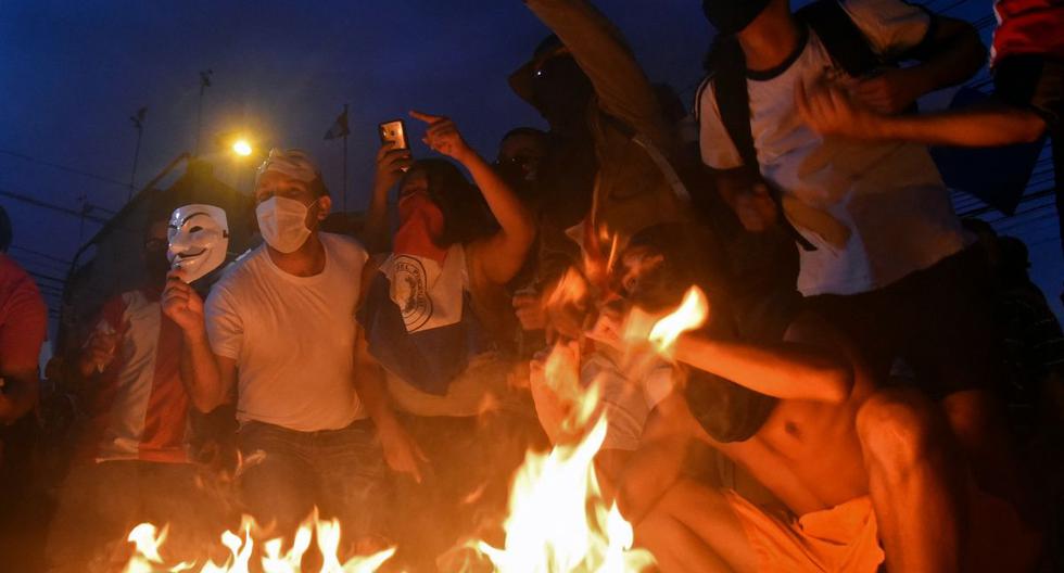 Manifestantes rodean una hoguera durante una protesta contra la corrupción y las carencias del sistema de salud, exigiendo la renuncia del presidente paraguayo Mario Abdo Benítez, frente al edificio del Congreso en Asunción, el 5 de marzo de 2021. (NORBERTO DUARTE / AFP).