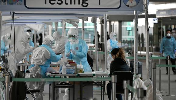 Personal médico toma muestras para diagnosticar coronavirus de un pasajero extranjero en una cabina de pruebas fuera de un aeropuerto internacional. (Foto: AFP/Jung Yeon-je)