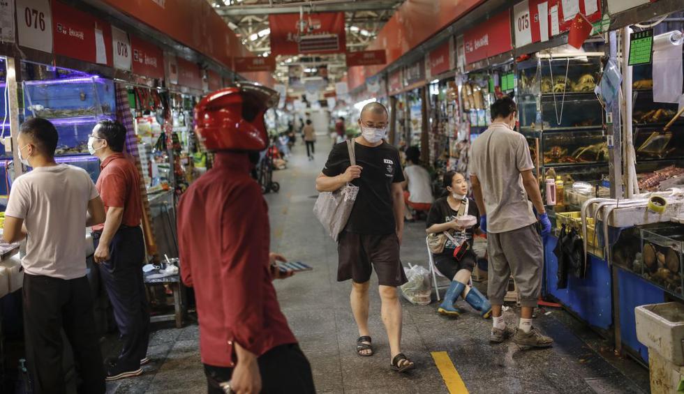 Ciudadanos con mascarillas contra el coronavirus pasan por los puestos de mariscos en un mercado en Beijing (China). (EFE/EPA/STRINGER).