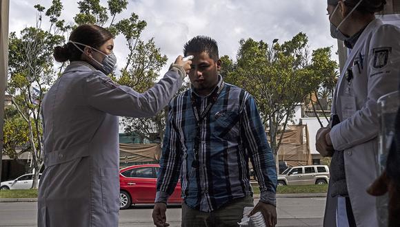 Una enfermera verifica la temperatura de un hombre en la entrada del Hospital General de Tijuana, en México, por la epidemia del coronavirus. (Foto: AFP)