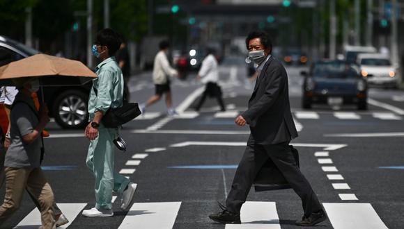 Las personas usan máscaras faciales mientras caminan por una calle de Tokio en medio del brote de COVID-19 que se vive en la ciudad. (Charly TRIBALLEAU / AFP)