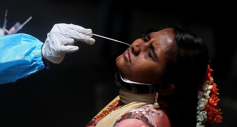 Un trabajador de la salud toma una muestra de hisopo nasal de una mujer para la prueba de coronavirus COVID-19 en la estación de tren de la ciudad de Bangalore, India, el 23 de abril de 2021. (EFE / EPA / JAGADEESH NV).