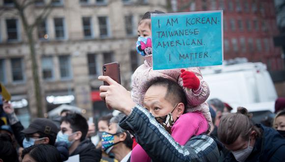 Un hombre cargando a su hijo quien sostiene una pancarta que dice "Soy coreano, taiwanés y americano. Yo importo", durante su participación en un evento, convocado por la Asian American Federation. (Foto: EFE)