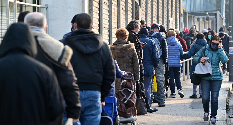 Personas necesitadas esperan antes de llevarse una bolsa con comida gratis en la asociación laica italiana, no partidista y sin fines de lucro llamada "Pane Quotidiano" (Pan de cada día) en Milán, el 8 de marzo de 2021. (MIGUEL MEDINA / AFP).