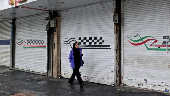 Una mujer pasa frente a una tienda cerrada a lo largo de la calle Satarkhan en la capital de Irán, Teherán, el 5 de diciembre de 2022. (Foto de ATTA KENARE / AFP)
