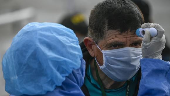 Un trabajador sanitario de Colombia revisa la temperatura de un transeúnte en Bogotá como medida preventiva contra la propagación del coronavirus. (Foto: AFP)