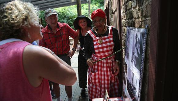 La narradora Gloria Barr Ford señala fotos de sus ancestros esclavos mientras hablaba con turistas en la plantación de Boone Hill. (Foto: AFP)