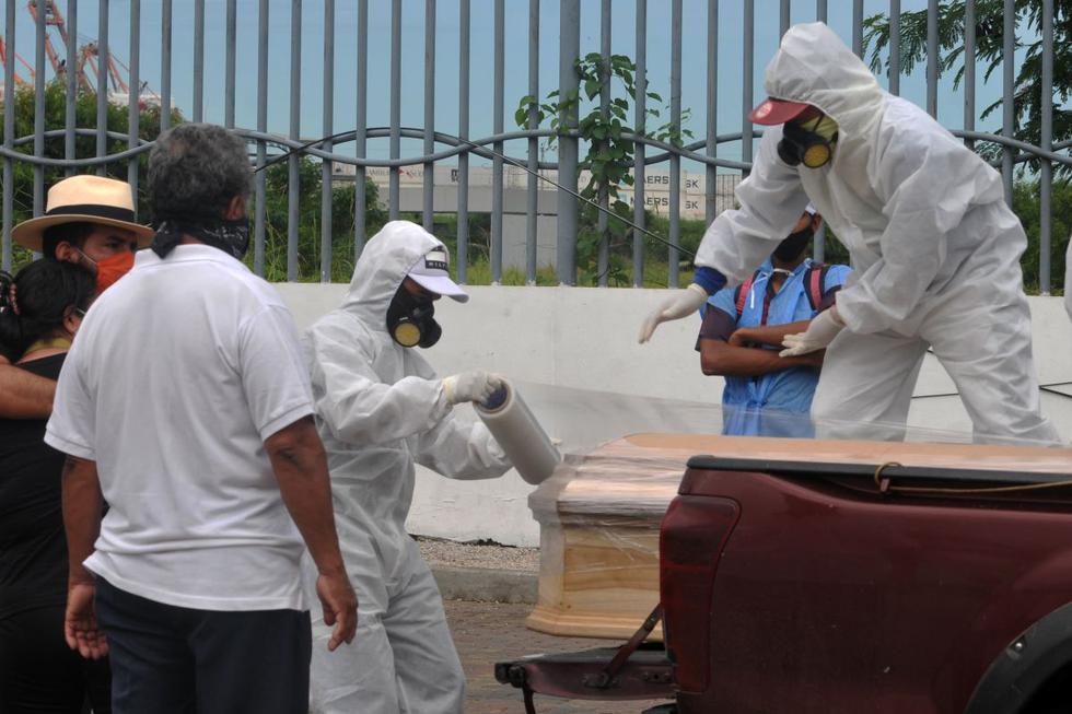Los trabajadores que usan trajes protectores envuelven en plástico un ataúd con los restos de una persona que murió por el coronavirus, afuera de la morgue del Hospital General Guasmo Sur en Guayaquil, Ecuador. (Foto: AFP/Jose Sánchez)