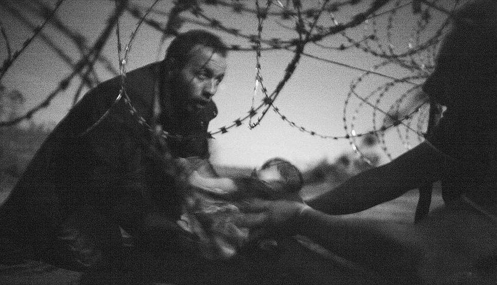 World Press Photo premia la imagen de un refugiado pasando a su bebé por una alambrada. (AFP)