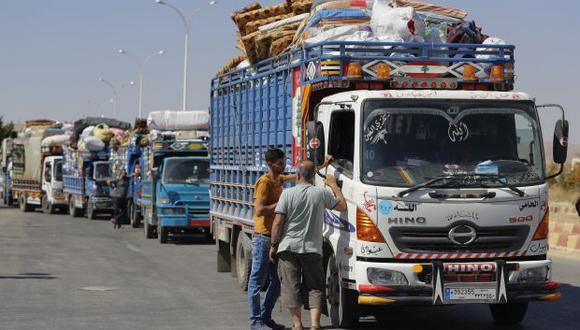 Refugiados sirios están parados junto a camiones con pertenencias en camino a Siria en el paso fronterizo de Jdedeh Yabous, Siria. Autoridades dicen que trabajan para reconstruir hospitales, escuelas y más para ayudar a los refugiados. (Foto: AP)