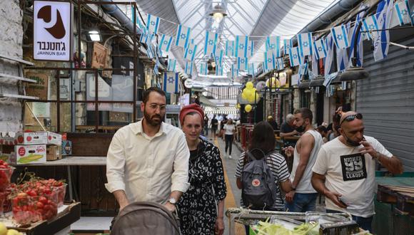 La gente compra en un mercado en Jerusalén, el 18 de abril de 2021, después de que las autoridades israelíes anunciaran que las mascarillas para la prevención del COVID-19 ya no eran necesarias al aire libre. (Menahem Kahana / AFP)